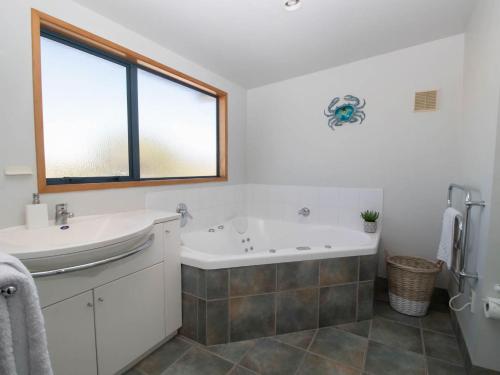 新普利茅斯Beachfront Bliss On Wanaka Terrace Support Local的带浴缸和盥洗盆的浴室