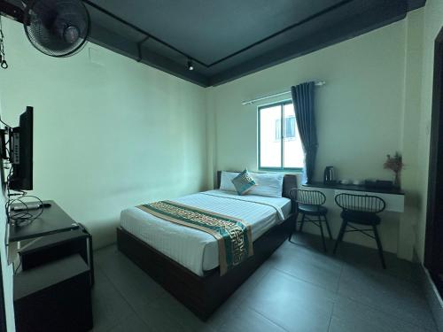 胡志明市Saigon Chill Hostel的一间卧室配有一张床、一张书桌和一个窗户。