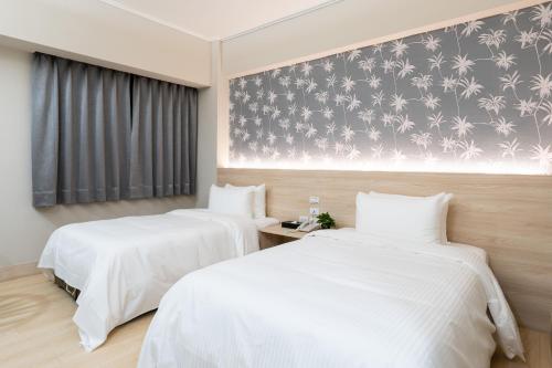 台中市怡东商务旅馆的配有白色床单的酒店客房内的两张床