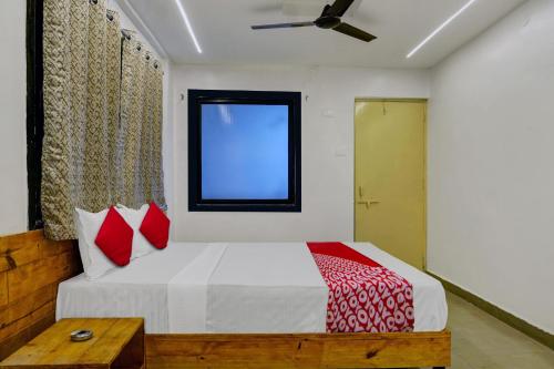 浦那OYO Hotel Paradise的一间卧室配有一张带红色枕头的床和一扇窗户