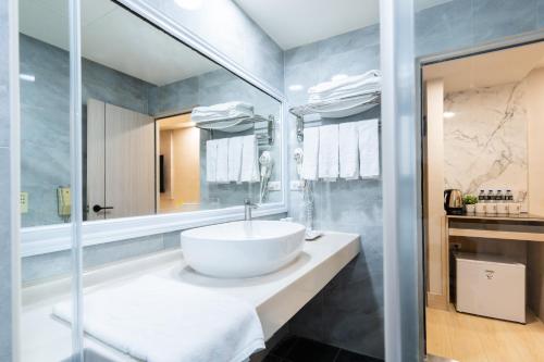 台中市怡东商务旅馆的浴室设有白色水槽和镜子