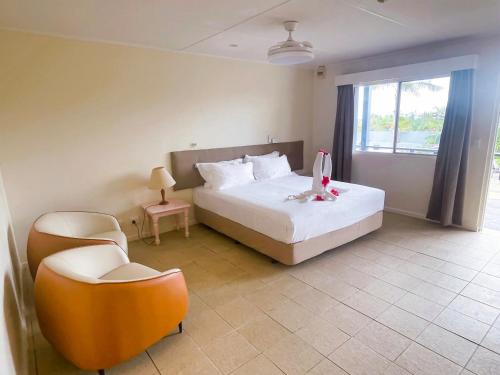 维拉港Coconut Palms Resort & Diamond Casino的卧室配有床、椅子和窗户。