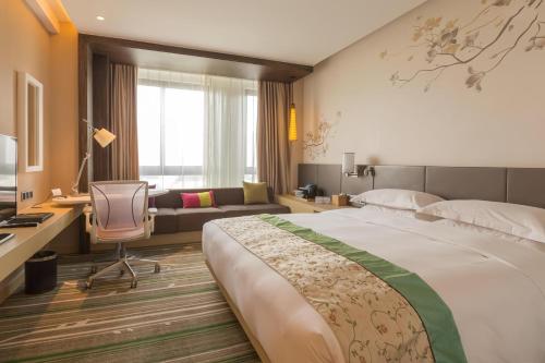 西安西安阳光城希尔顿花园酒店的酒店客房设有一张大床和一张书桌。