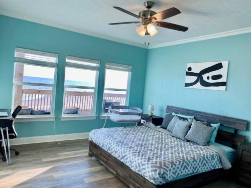 卡梅伦OceanFront home near HollyBeach的一间卧室设有蓝色的墙壁和一张带吊扇的床。