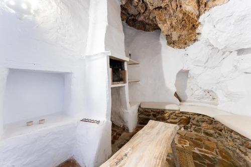米哈斯La Cueva的一间设有白色墙壁和木板凳的房间