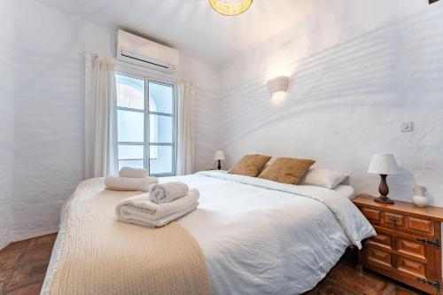 米哈斯La Cueva的白色卧室配有一张大床和毛巾