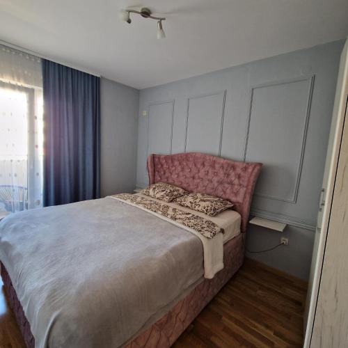 波德戈里察Stefanija的一间卧室配有一张带粉红色床头板的大床