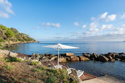 马西亚娜马里纳Villa Escalina with private beach and A/C的海滩上的一组椅子和一把遮阳伞