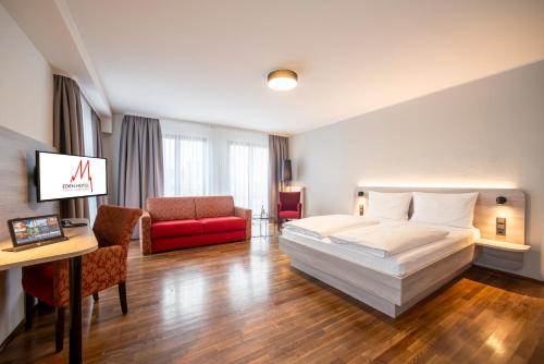科隆多姆弗瑞赫伊登酒店的酒店客房,配有一张床和一张红色的沙发