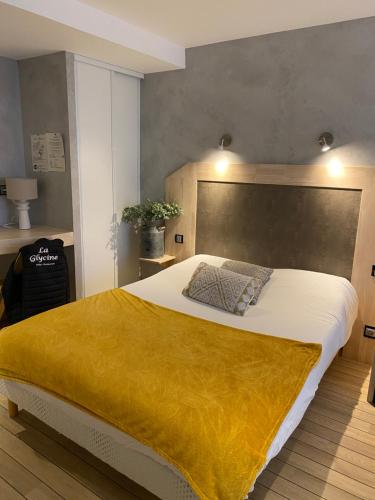 贝努维尔Hôtel Bien Être La Glycine的一间卧室配有一张带黄色毯子的大床