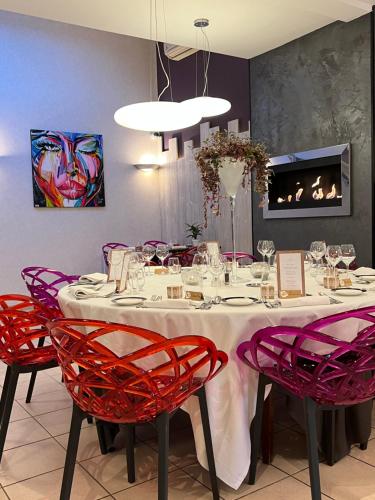 贝努维尔Hôtel Bien Être La Glycine的一间带红色椅子的餐桌的用餐室