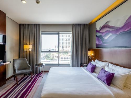 迪拜Flora Al Barsha Hotel At The Mall的酒店客房配有一张带紫色枕头的大床