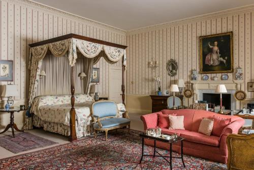 艾尔斯伯里哈特韦尔别墅&SPA的一间卧室配有天蓬床和红色沙发