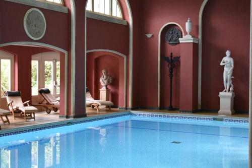 艾尔斯伯里哈特韦尔别墅&SPA的一座大型游泳池,位于一座拥有红色墙壁的建筑中