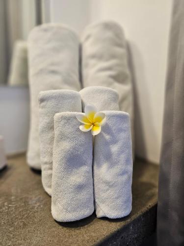 乌布Chandi Hotel Ubud的上面有三条白色毛巾和黄色花