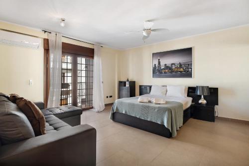阿德耶Villa Rossella By Paramount Holidays的一间卧室配有一张床、一张沙发和一把椅子