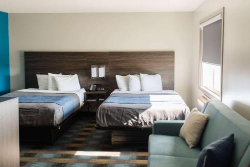 埃斯卡诺巴Travelodge by Wyndham Escanaba的酒店客房,设有两张床和一张沙发