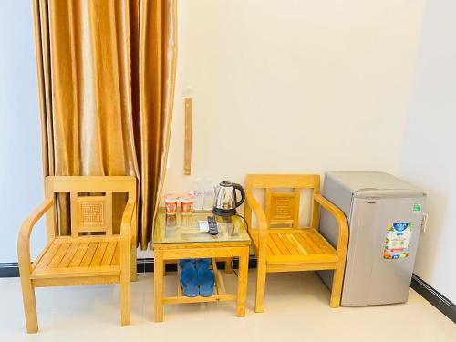 Ninh HảiHotel Aloha 2的桌子、两把椅子和小冰箱