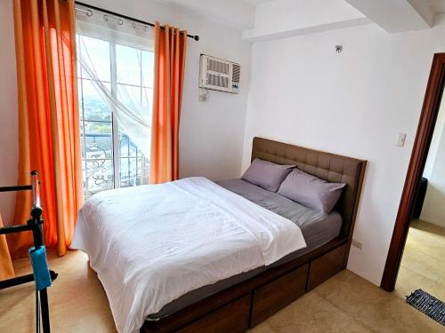 宿务AppleOne CondoTower1-1055的一间卧室配有带橙色窗帘的床和窗户