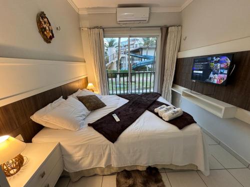 阿奎拉兹Beach Living, Frente mar, 400m do B Park com Restaurante e Toboagua的一间卧室配有一张带白色床单的床和一扇窗户。