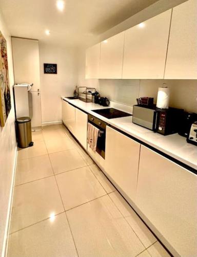 伦敦H1: Stunning Large Apt - Under 100m to Piccadilly Circus!的厨房配有白色橱柜和冰箱。