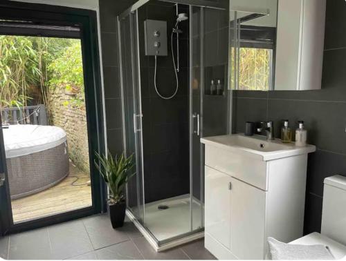布里斯托1 bedroom rural cabin retreat with hot tub in Hambrook close to Bristol city centre的带淋浴、盥洗盆和浴缸的浴室