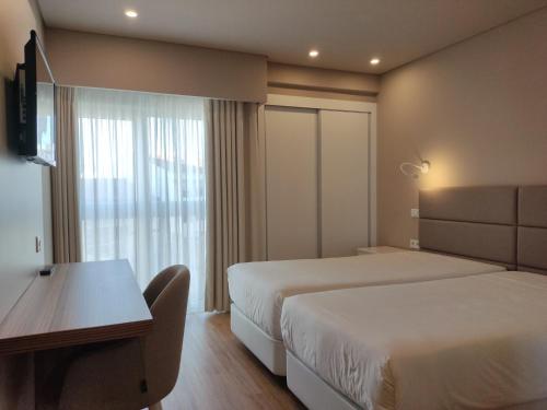 卡尔达斯达·赖尼亚卡尔达斯酒店的酒店客房设有两张床、一张书桌和一个窗户。