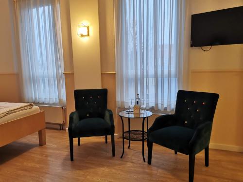 库克斯港戴赫沃格特酒店的酒店客房的两张椅子和一张桌子