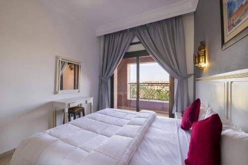 马拉喀什莫加多尔门扎公寓酒店的卧室配有带红色枕头的大型白色床