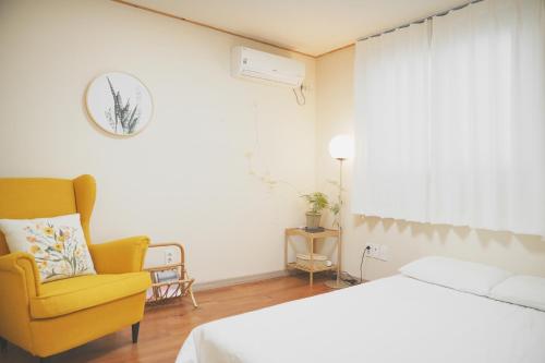 西归浦市Entire House with Garden - Warm water Jacuzzi的一间卧室配有一张床和一张黄色椅子