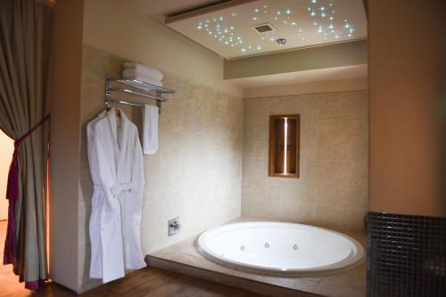 班克内克Glenskirlie Castle Hotel的一间带大浴缸和浴袍的浴室