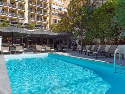巴塞罗那H10大都会4 *索普酒店的一座带椅子的大型游泳池和一座建筑