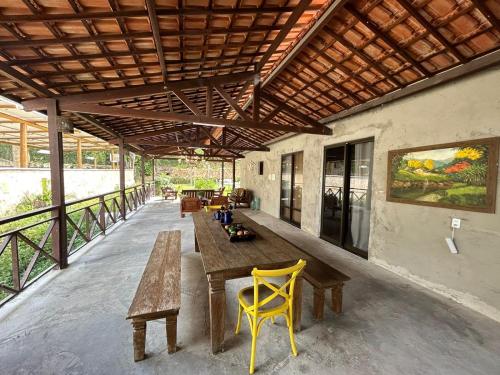 瓜拉米兰加Pousada Monte Flor Guaramiranga CE的庭院配有木桌和黄色椅子