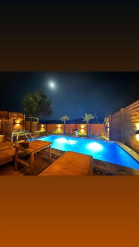 萨卡里亚Sapanca360bungalows的夜间游泳池,配有野餐桌和长椅
