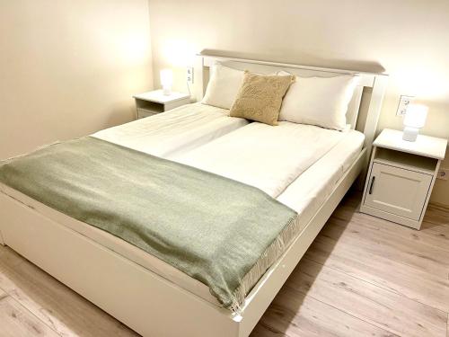 毛科Vörösmarty apartmanház的一间卧室配有一张带2个床头柜的大型白色床