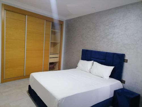 丹吉尔Apartment chakira family only的一间卧室配有一张白色的床和蓝色床头板