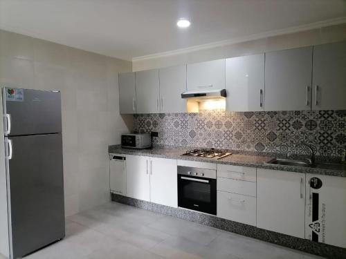 丹吉尔Apartment chakira family only的厨房配有白色橱柜和不锈钢冰箱
