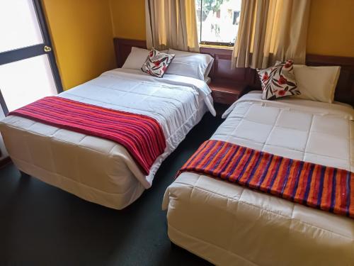 瓦拉斯Huaraz Center Hostal的两张睡床彼此相邻,位于一个房间里