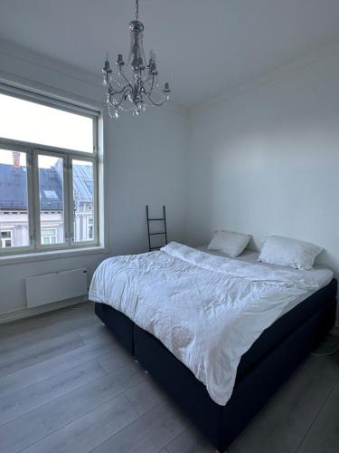 奥斯陆sjarmerende leilighet i hjertet av Oslo的白色卧室配有一张床和一个吊灯