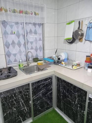 拉布安Orchid Homestay的厨房配有黑色大理石台面和水槽