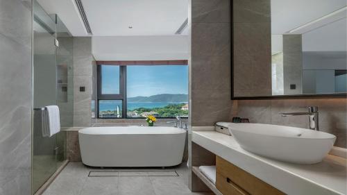 三亚三亚亚龙湾星华套房假日酒店的浴室配有大型白色浴缸和水槽