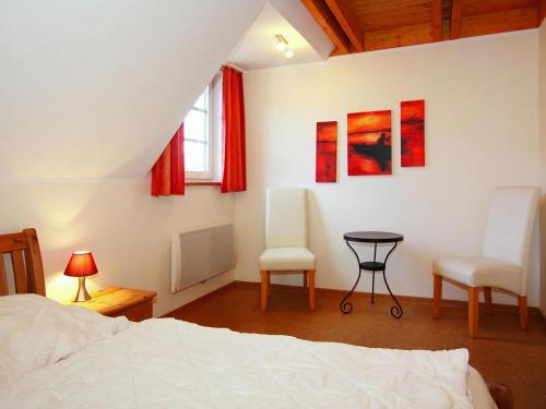 特拉森海德Apartment in Trassenheide with sauna的一间卧室配有一张床、两把椅子和一张桌子