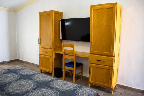 Hotel Boutique Casa Tellez的一间卧室配有书桌、电视和木制橱柜