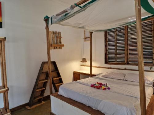 UtendeMafia Island Bungalows的一间卧室配有一张带梯子和鲜花的床。