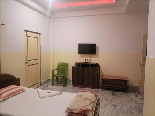 拉塔古里Hotel Sonali的一间卧室配有一张床、一台电视和两张绿色椅子