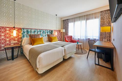 塞维利亚塞维利亚赫斯珀里亚酒店的一间卧室配有一张大床和一张桌子及椅子
