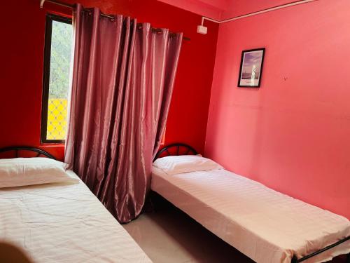 苏瓦Grace house的宿舍间的两张床,设有红色的墙壁和窗户。