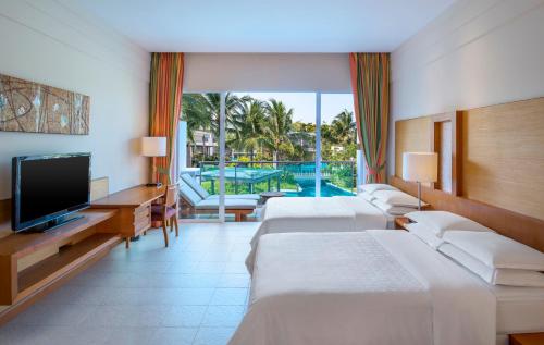 七岩Sheraton Hua Hin Resort & Spa的酒店客房设有三张床和电视。