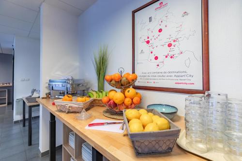 里摩日Appart'City Classic Limoges的厨房在柜台上放有橘子和其他水果碗