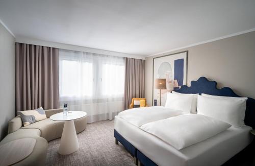 维也纳voco Vienna Prater, an IHG Hotel的酒店客房设有一张大床和一张沙发。